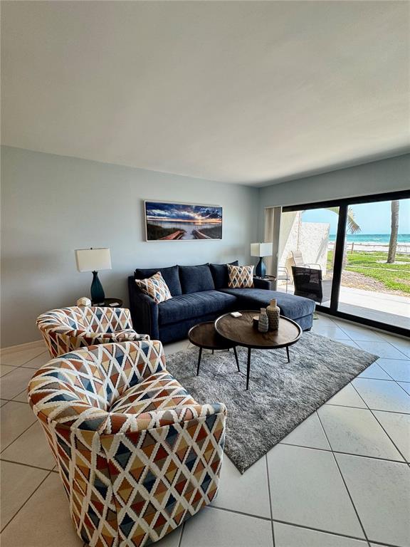 A living room features a blue sectional, patterned armchairs, and a sliding door to a beach — 2089 GULF OF MEXICO DRIVE UNIT G1-108, LONGBOAT KEY, FL