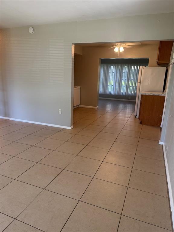 A tiled living area opens into a kitchen featuring wooden cabinets and a white refrigerator — 5232 KAPOK DRIVE, NEW PORT RICHEY, FL