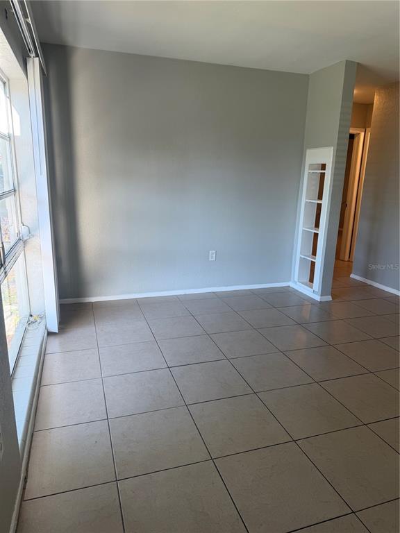 An empty room features light-colored tile flooring, gray walls, and a built-in white shelving unit — 5232 KAPOK DRIVE, NEW PORT RICHEY, FL