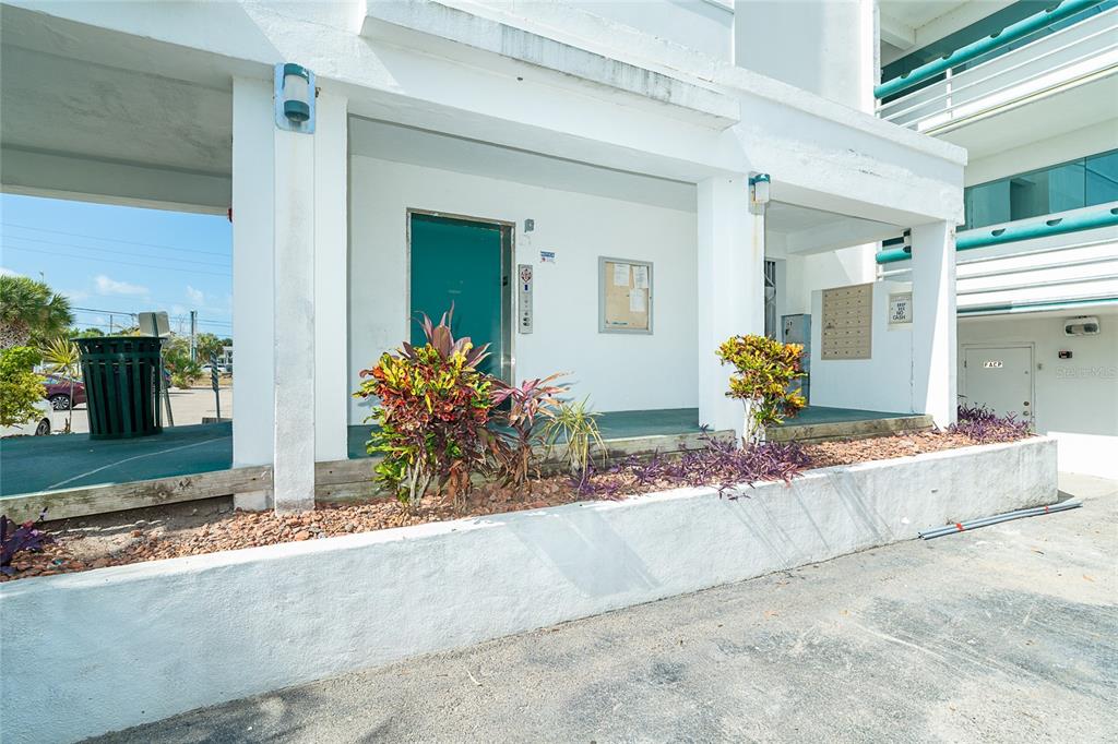 The exterior of a white building features a covered entrance with a green door — 1460 S MCCALL ROAD UNIT E3, ENGLEWOOD, FL