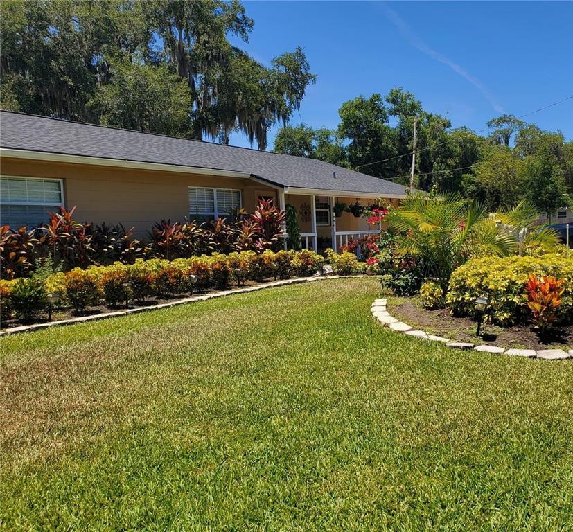 A single-story house with a tan exterior, a covered porch, and landscaped front yard — 916 VERMONT AVENUE, ST CLOUD, FL
