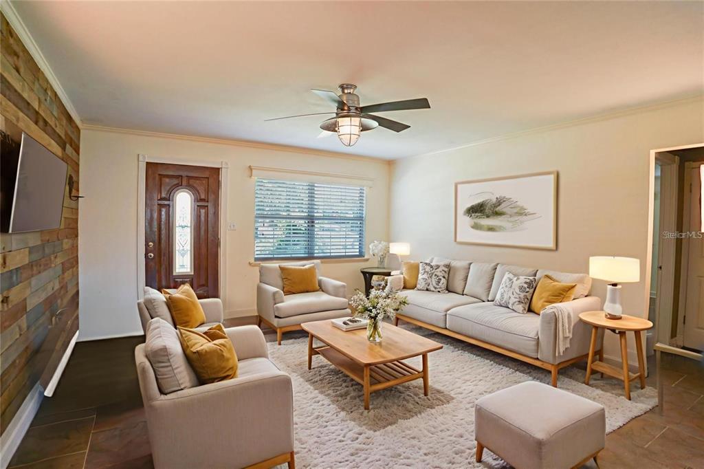 A living room features a wood-paneled accent wall, neutral furniture, and a central ceiling fan — 916 VERMONT AVENUE, ST CLOUD, FL