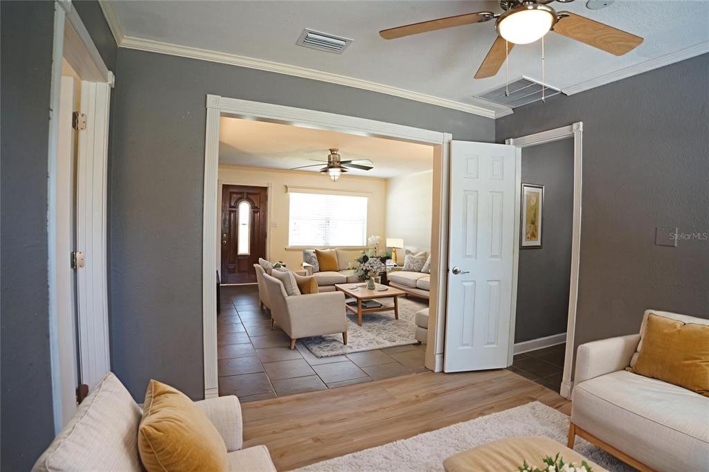 A living room with gray walls and wood-look flooring opens into a tiled sitting area — 916 VERMONT AVENUE, ST CLOUD, FL