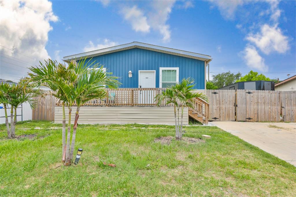 A blue single-story house features a wooden deck, front stairs, and a fenced yard — 1169 8TH AVENUE NE, LARGO, FL