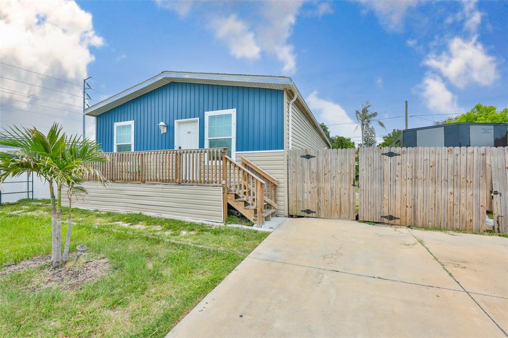 A blue and beige manufactured home features a wooden deck and a concrete driveway — 1169 8TH AVENUE NE, LARGO, FL