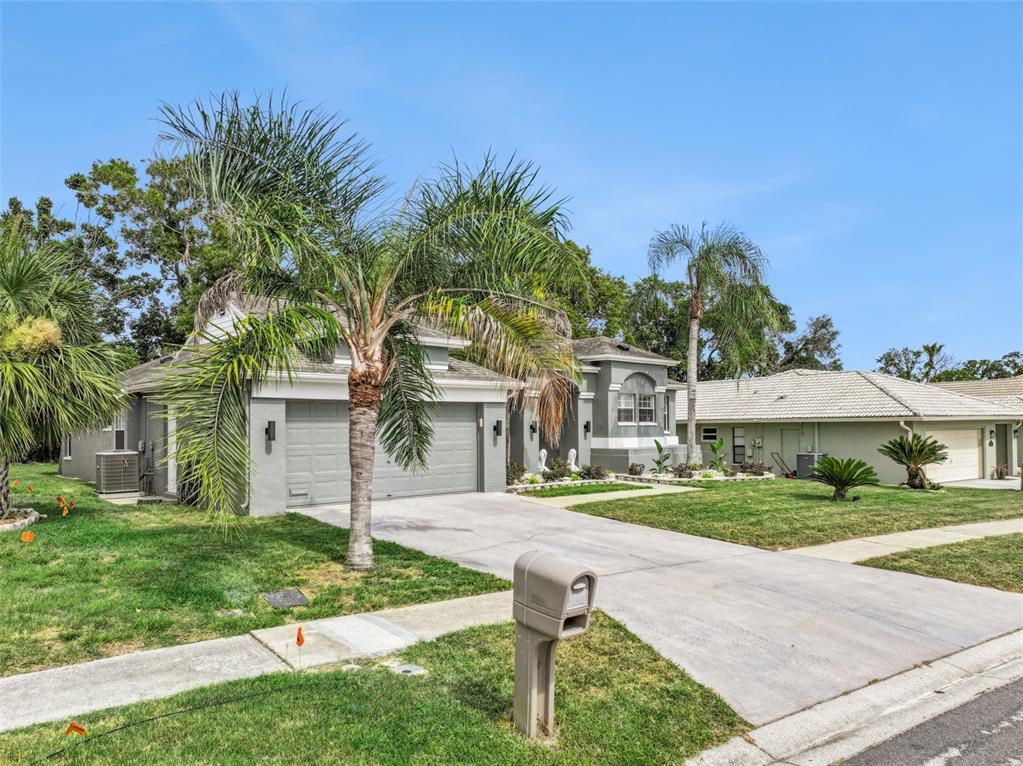 A gray house with a two-car garage and a palm tree in the front yard — 1236 LANSING DRIVE, SPRING HILL, FL