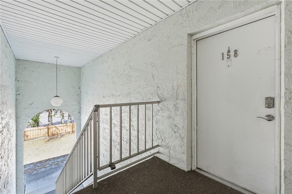 A white door labeled 158 stands at the top of a staircase with metal railings — 337 S MCMULLEN BOOTH ROAD UNIT 158, CLEARWATER, FL