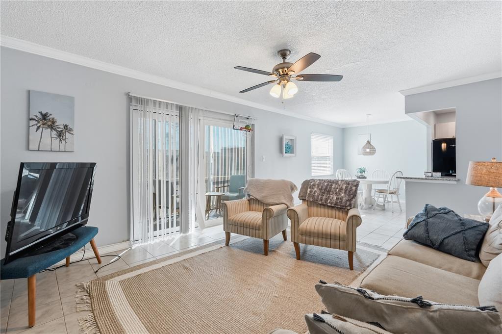 A living room with tile floors, two striped armchairs, a television, and a ceiling fan — 337 S MCMULLEN BOOTH ROAD UNIT 158, CLEARWATER, FL