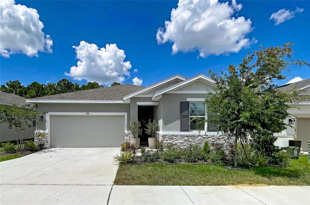 A single-story house with a gray exterior, stone veneer, and a two-car garage — 858 BALLANTYNE DRIVE, LAKE WALES, FL