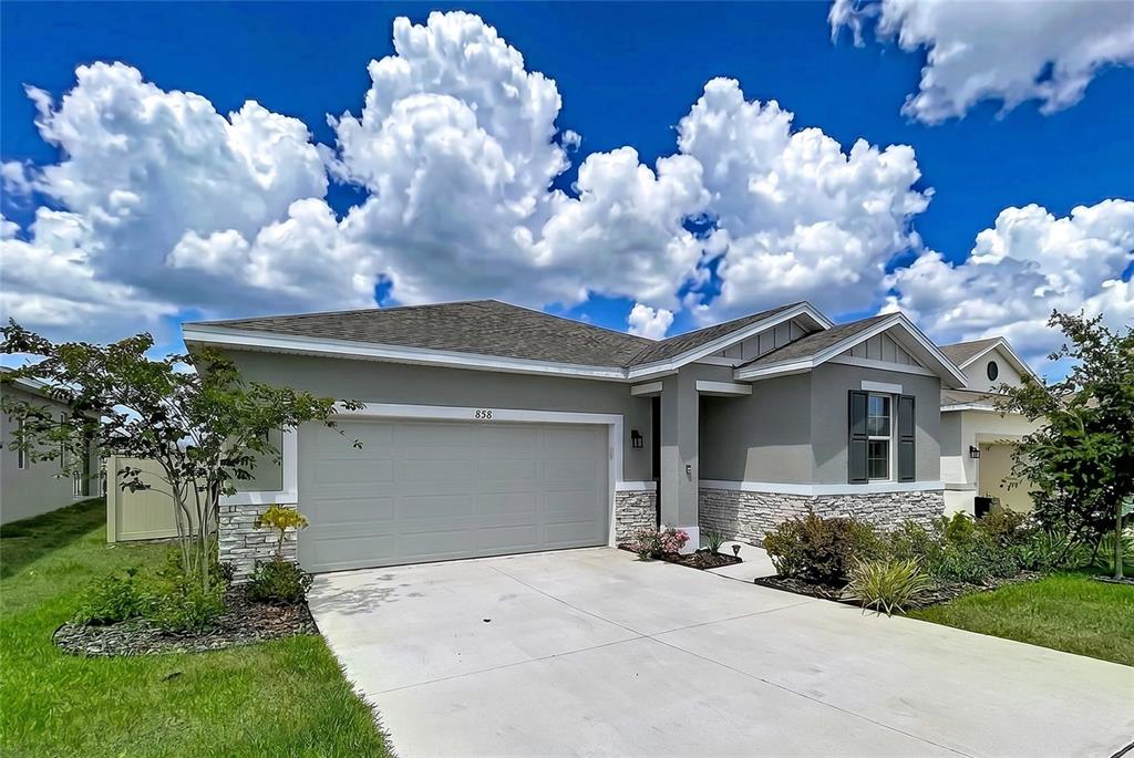 A single-story house features a gray stucco exterior, stone veneer accents, and a two-car garage — 858 BALLANTYNE DRIVE, LAKE WALES, FL