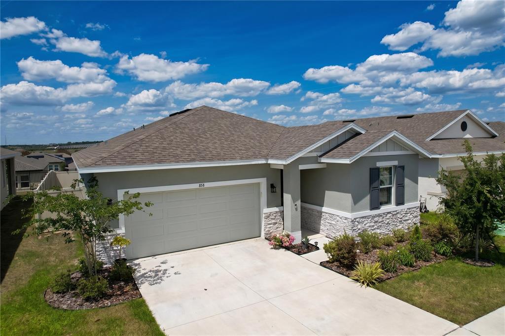A single-story house with a two-car garage, stone veneer accents, and a shingled roof — 858 BALLANTYNE DRIVE, LAKE WALES, FL