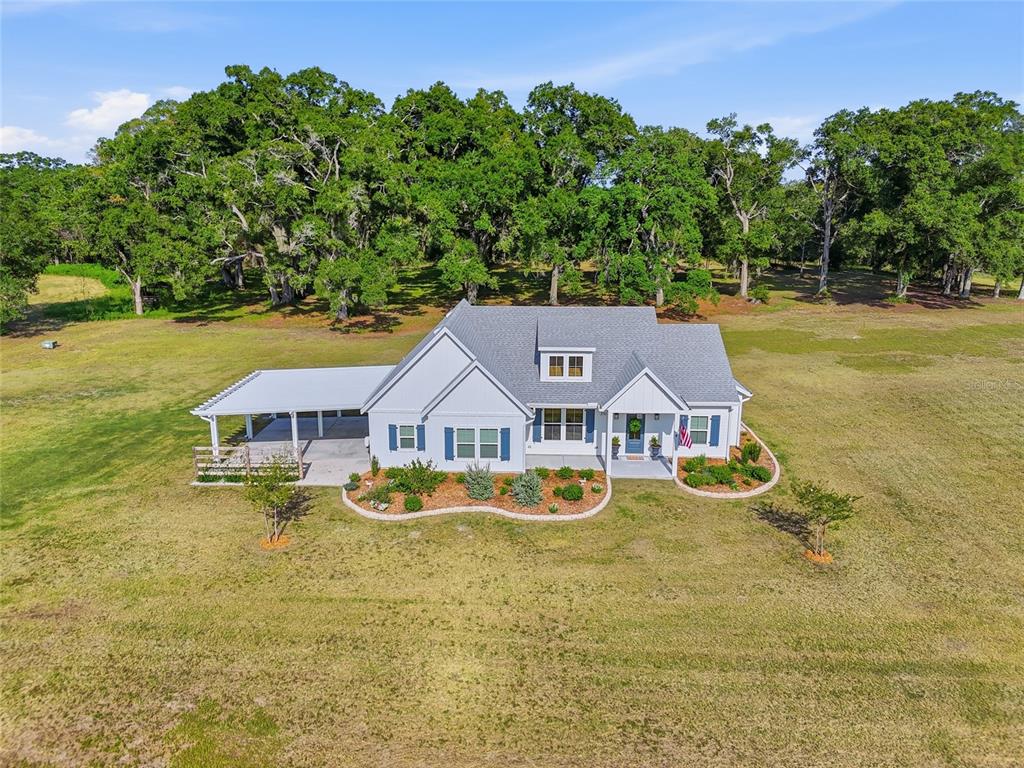 An aerial view of a white single-story house with a metal carport and landscaping — 3705 NW 31ST AVENUE, BELL, FL