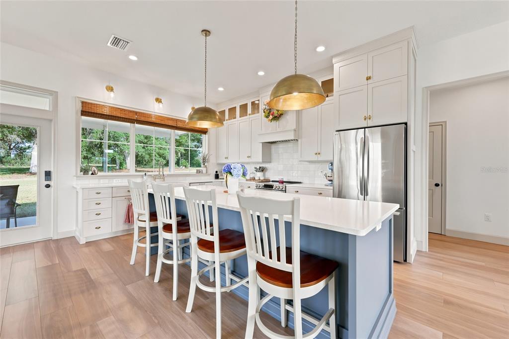 A kitchen features a blue island with bar stools, white cabinetry, and stainless steel appliances — 3705 NW 31ST AVENUE, BELL, FL
