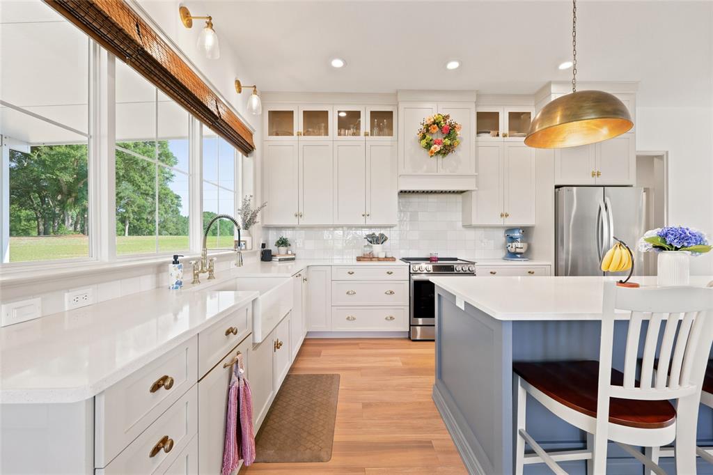 A kitchen features white cabinetry, a blue island, quartz countertops, and a large window view — 3705 NW 31ST AVENUE, BELL, FL
