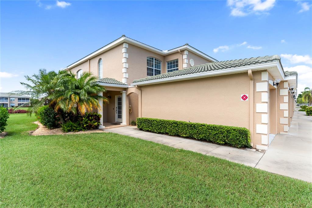 A tan two-story townhouse with a tile roof, a palm tree, and a concrete walkway — 6616 7TH AVENUE CIRCLE W UNIT 1311, BRADENTON, FL