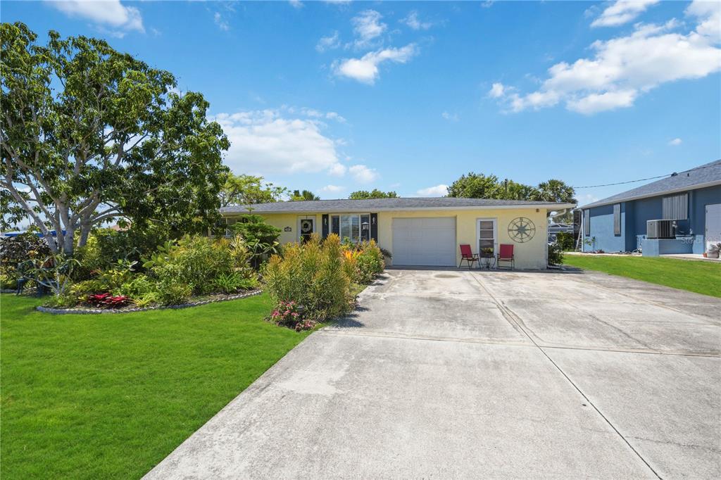 A single-story yellow house with a concrete driveway, a garage, and a landscaped front yard — 885 E 3RD STREET, ENGLEWOOD, FL
