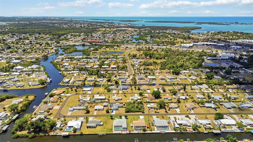 An aerial view shows a residential neighborhood with houses situated along canals near the coast — 885 E 3RD STREET, ENGLEWOOD, FL