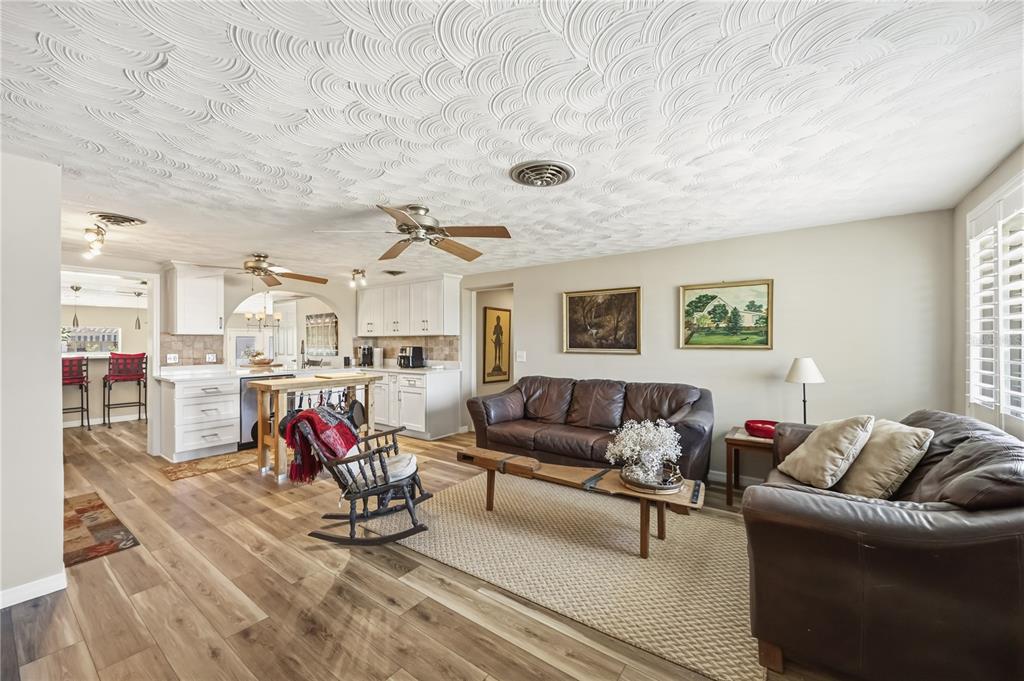 An open-concept living room and kitchen featuring wood-look flooring and a textured swirl ceiling — 885 E 3RD STREET, ENGLEWOOD, FL