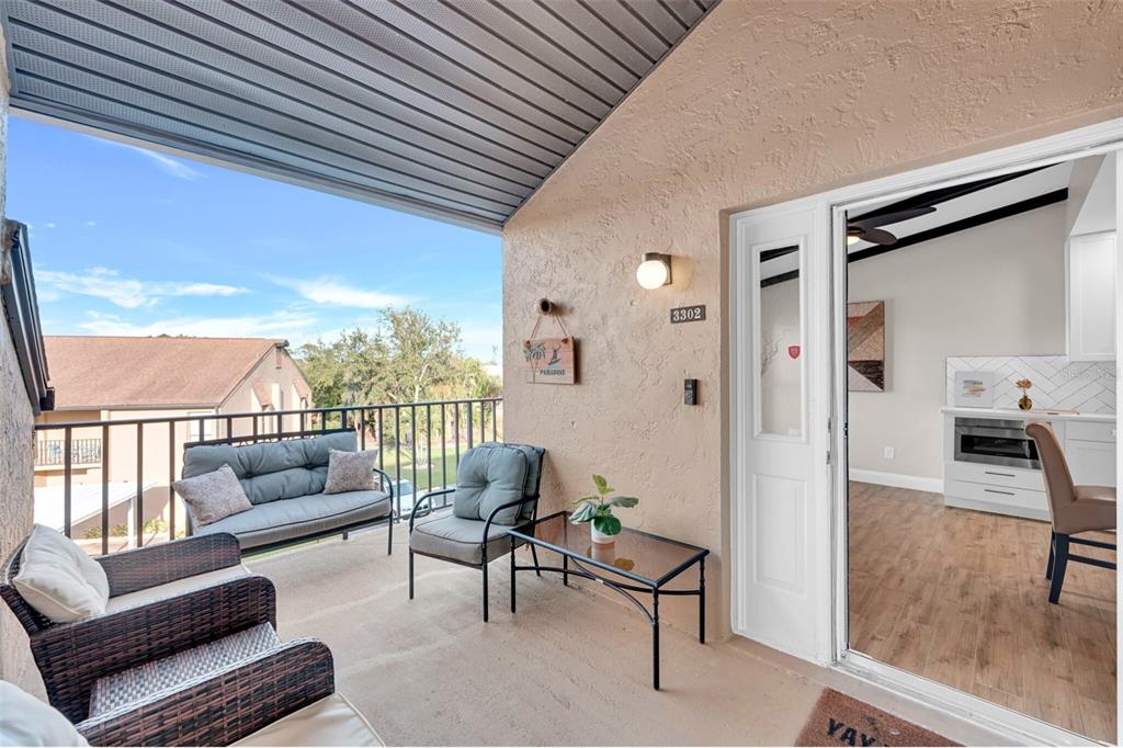 A balcony with outdoor furniture overlooks a residential area next to a glass sliding door — 15761 WINDWARD WAY CIRCLE UNIT 3302, FORT MYERS, FL