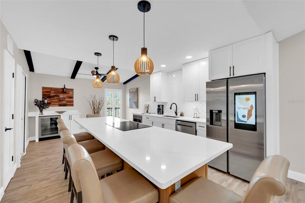 A modern kitchen features a large white quartz island, stainless steel appliances, and pendant lighting — 15761 WINDWARD WAY CIRCLE UNIT 3302, FORT MYERS, FL
