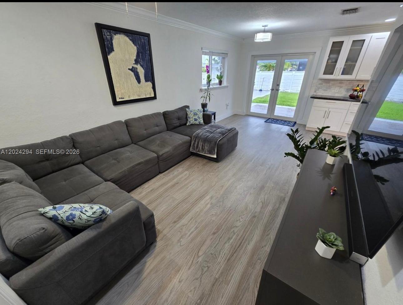A living room features a large gray sectional sofa, wood-look flooring, and glass patio doors — 9591 SW 52nd Ter, Miami FL 33165, MIAMI, FL