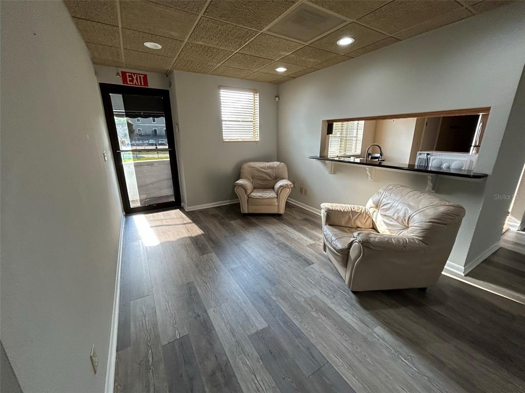 A room with wood-look flooring, two beige armchairs, a pass-through window, and a drop ceiling — 118 SW FORT KING STREET, OCALA, FL