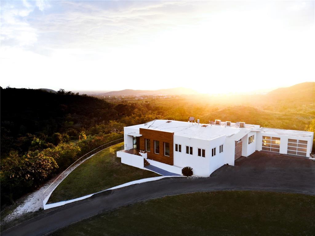 An aerial view of a modern white house with wood accents and a paved driveway — KM 0.7 PR-551, JUANA DIAZ, PR