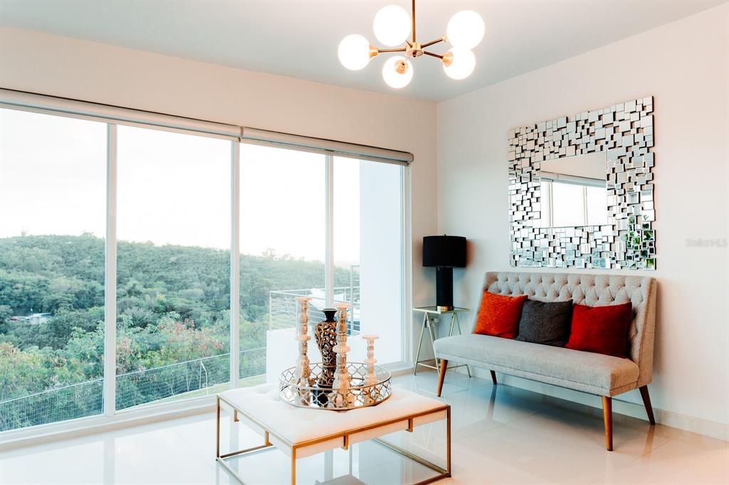 A modern living room features a tufted bench, a mirrored wall, and floor-to-ceiling windows — KM 0.7 PR-551, JUANA DIAZ, PR