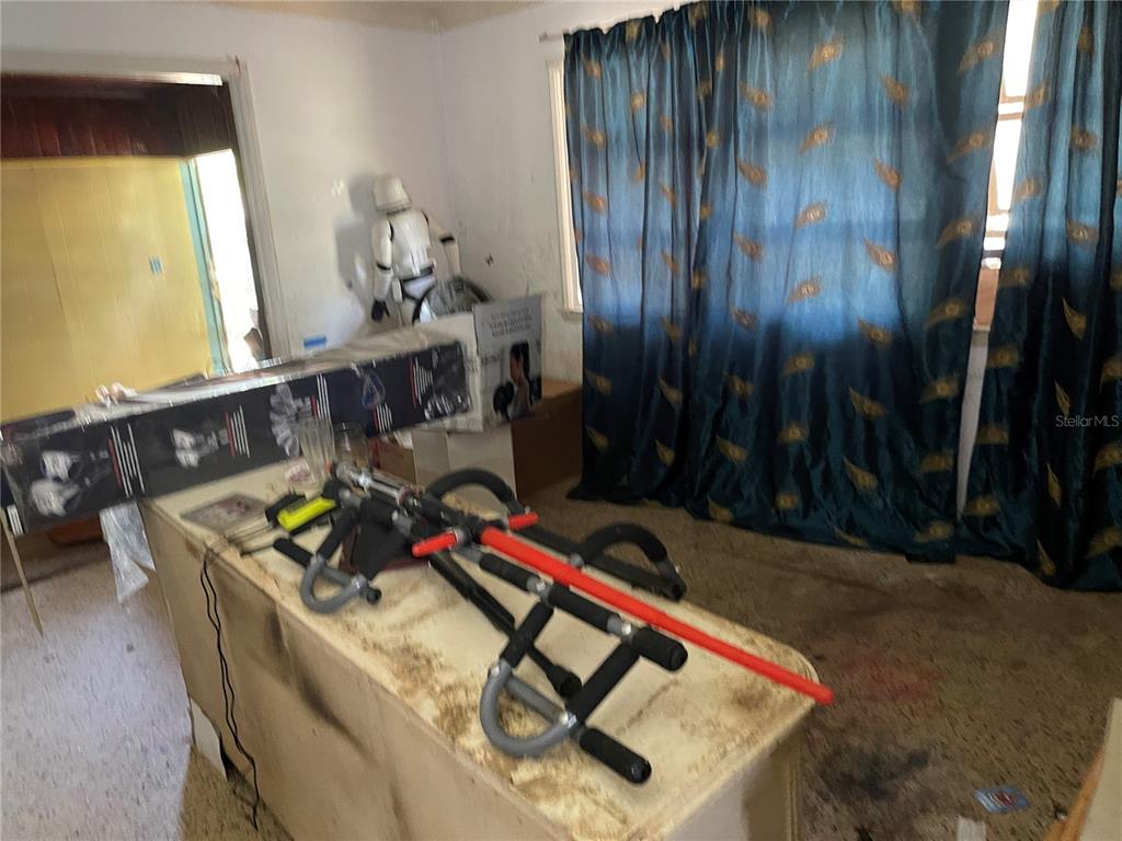 A room contains a fitness machine, a stormtrooper figure, and blue curtains over a window — 1311 S BRINK AVENUE, SARASOTA, FL