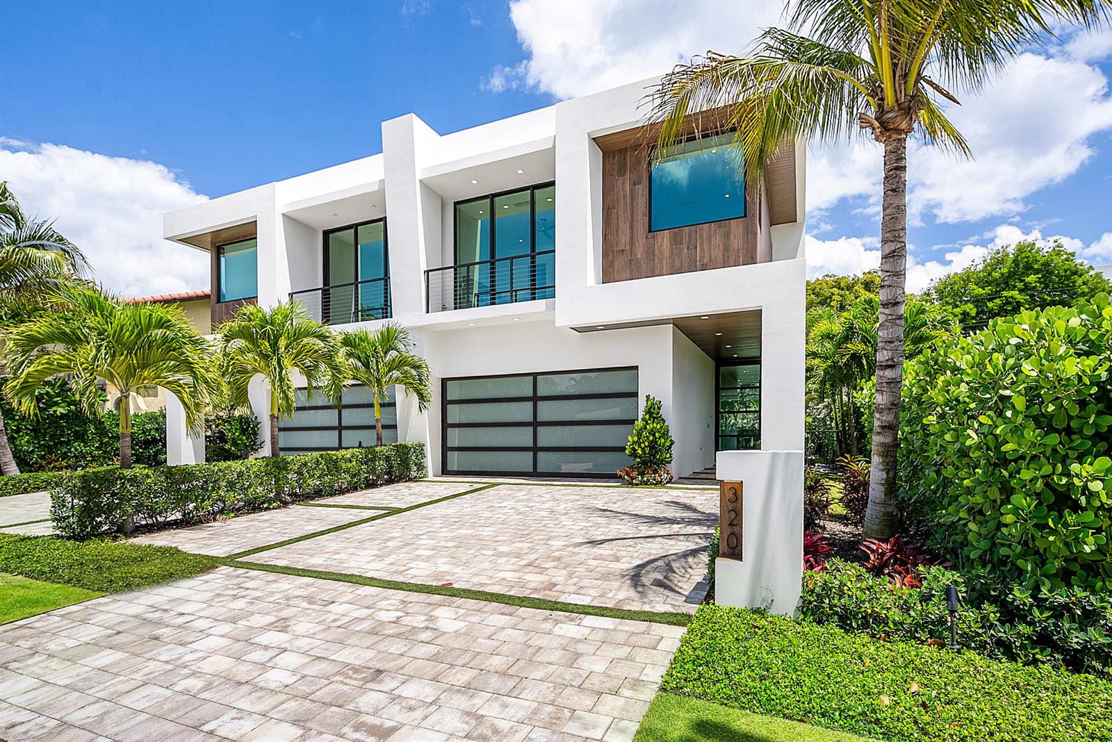 A modern two-story white house with a paved driveway, palm trees, and glass garage doors — 320 NE Wavecrest Way, Boca Raton FL 33432, BOCA RATON, FL