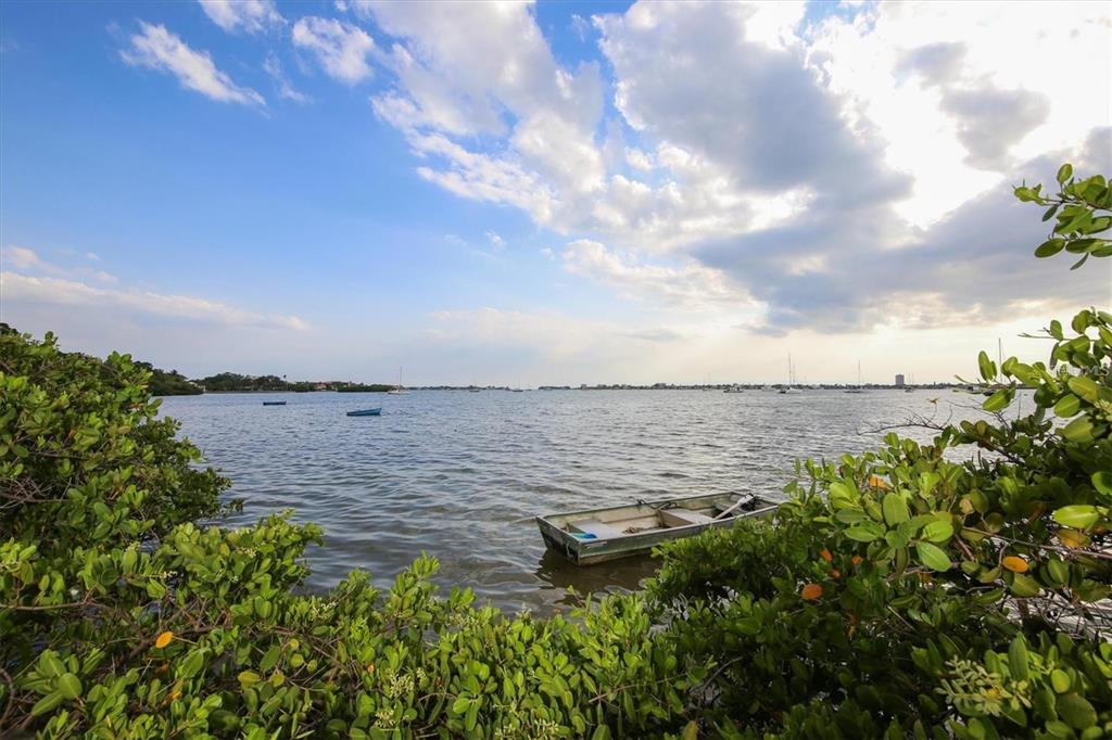 A small boat floats in a bay surrounded by lush green foliage under a cloudy sky — 1111 N GULFSTREAM AVENUE UNIT 16C, SARASOTA, FL