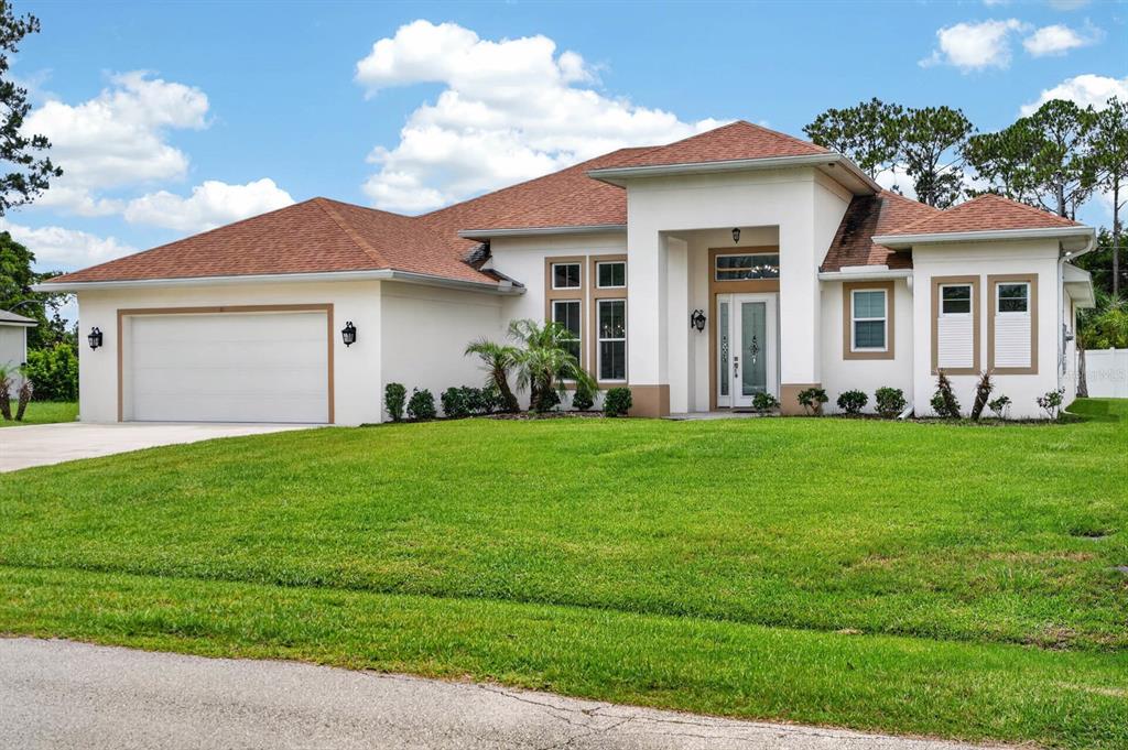 A single-story house with a white stucco exterior, brown roof, and a two-car garage — 19 WESTCHESTER LANE, PALM COAST, FL