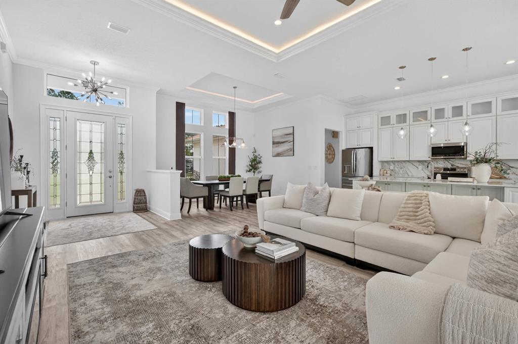 An open-concept living room features a white sectional sofa, a dining area, and a kitchen — 19 WESTCHESTER LANE, PALM COAST, FL