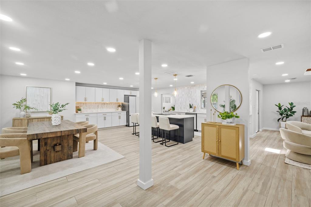 An open-concept kitchen and dining area features white cabinetry, a wooden table, and tile flooring — 1905 ORO COURT, CLEARWATER, FL