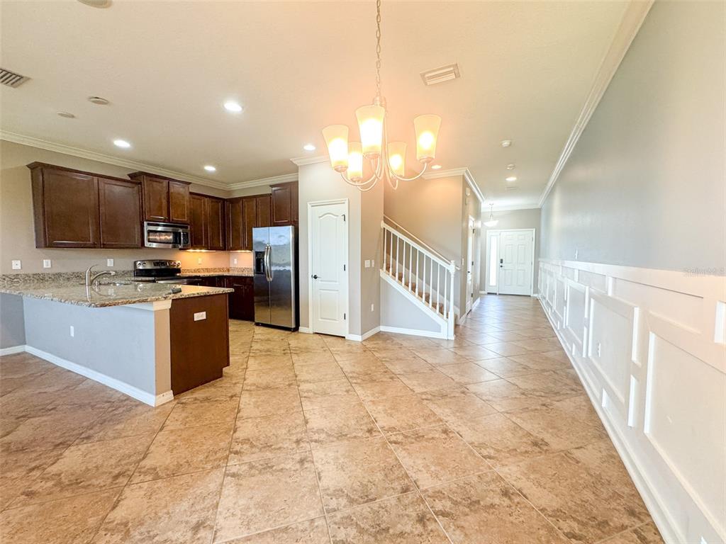 A kitchen with dark cabinets and granite countertops opens to a tiled dining area — 27015 JUNIPER BAY DRIVE, WESLEY CHAPEL, FL