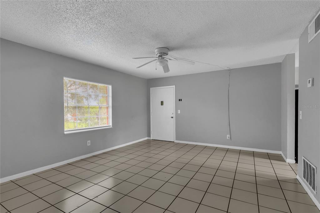 An empty room with gray walls, a white ceiling fan, and light-colored tile flooring — 1629 W OAK RIDGE ROAD UNIT 1629D, ORLANDO, FL