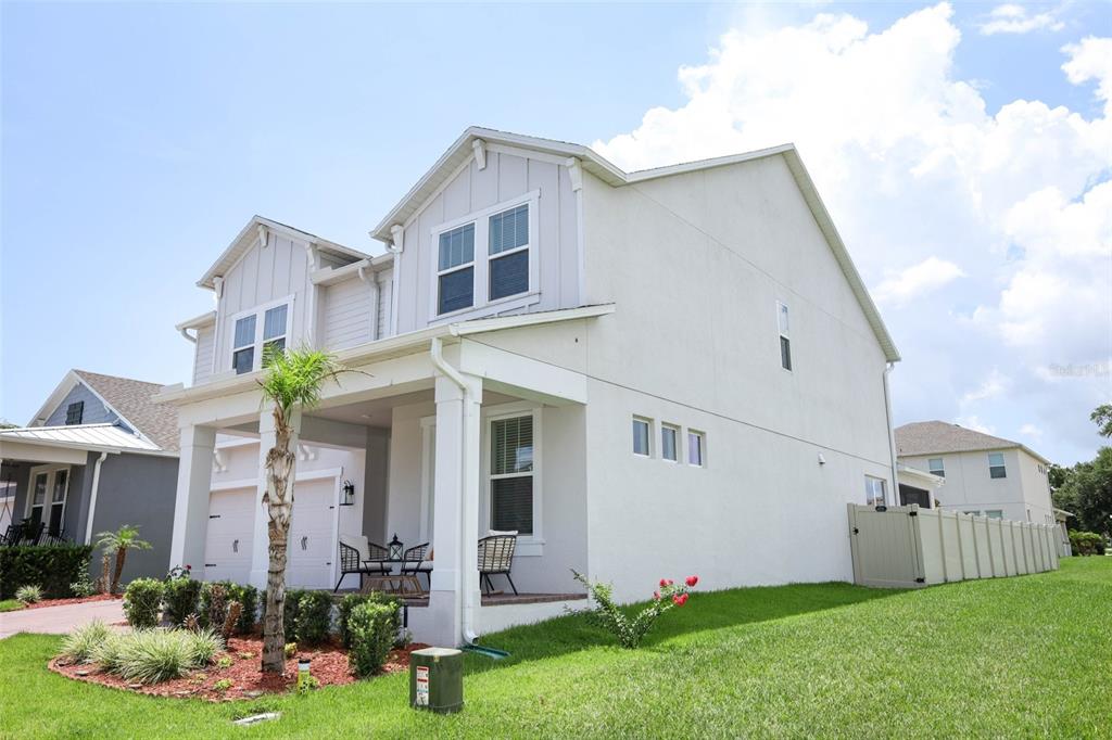 A two-story house with a covered front porch, light-colored stucco siding, and a grassy yard — 2010 BOSS HEWETT STREET, WINTER GARDEN, FL