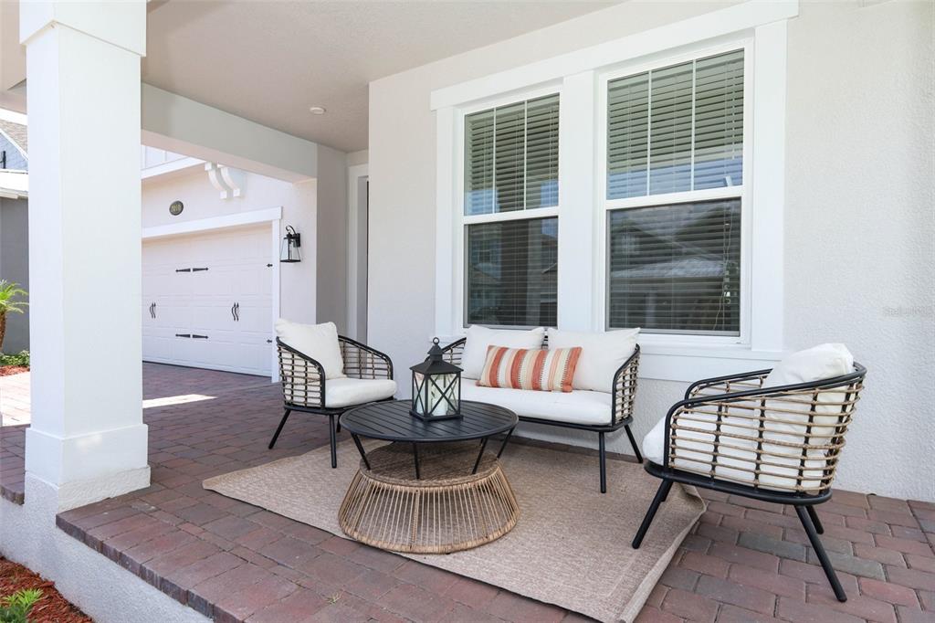 A covered brick patio features a seating area with two chairs, a bench, and a table — 2010 BOSS HEWETT STREET, WINTER GARDEN, FL