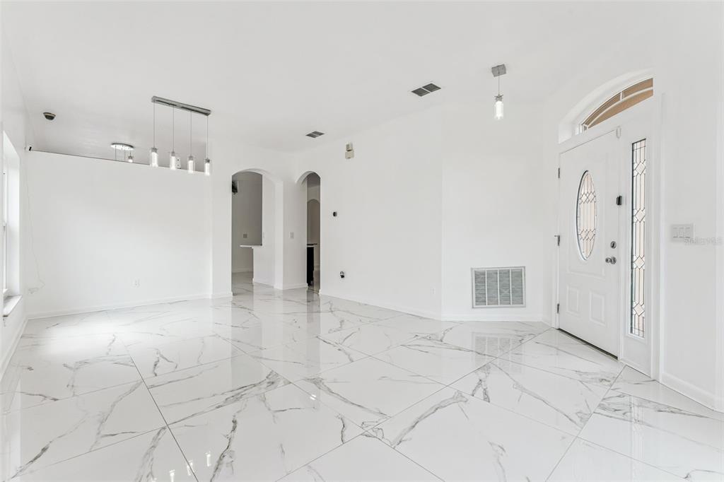 An entryway with white marble-look tile flooring, a white front door, and a modern chandelier — 8915 VICTORIA ISLE PLACE, ORLANDO, FL