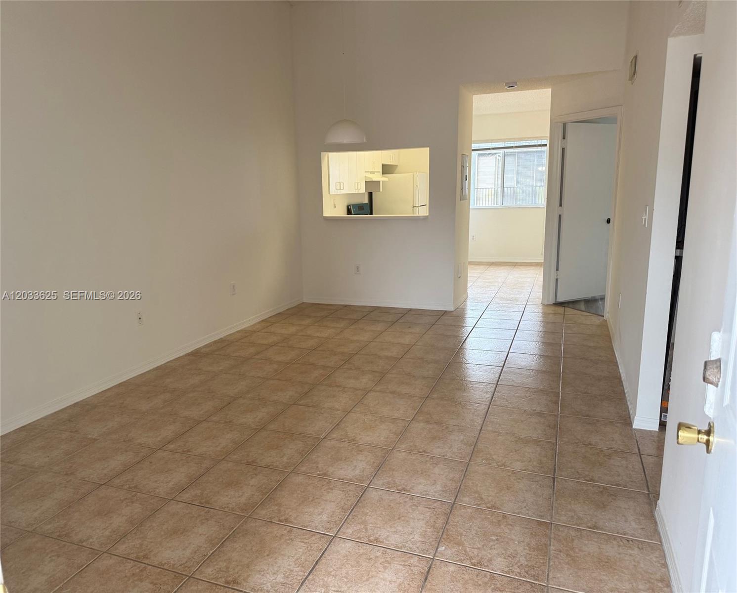 An interior view shows a tiled living area with a kitchen pass-through window — 13120 SW 64th Ter # 1504, Miami FL 33183, MIAMI, FL