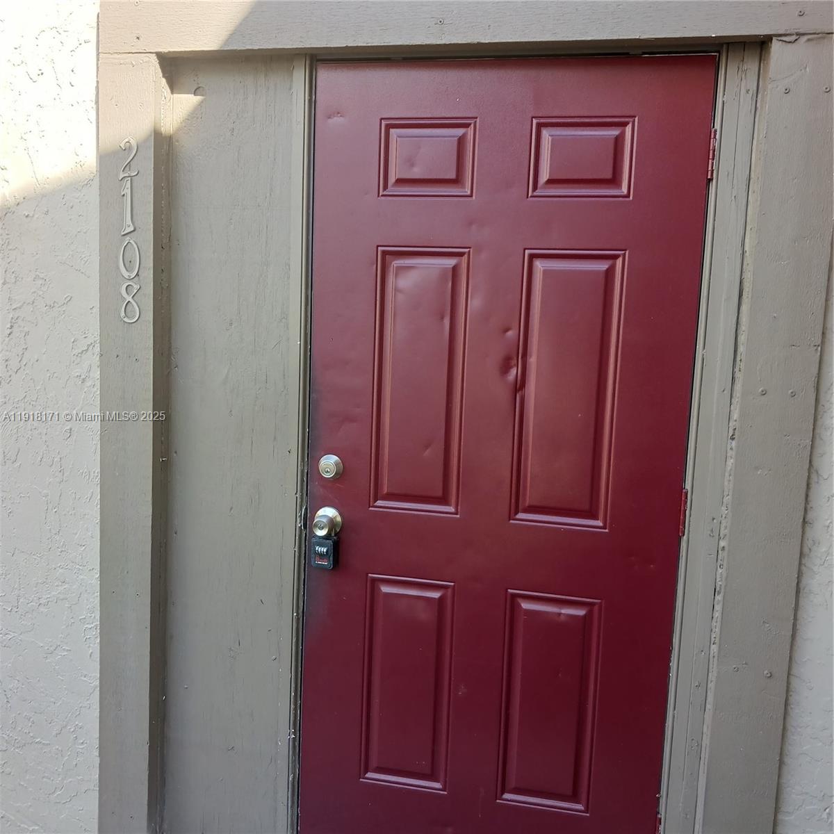 A red, six-panel metal door with a lockbox is set within a tan exterior frame — 2108 NW 59th Ter # A, Lauderhill FL 33313, LAUDERHILL, FL