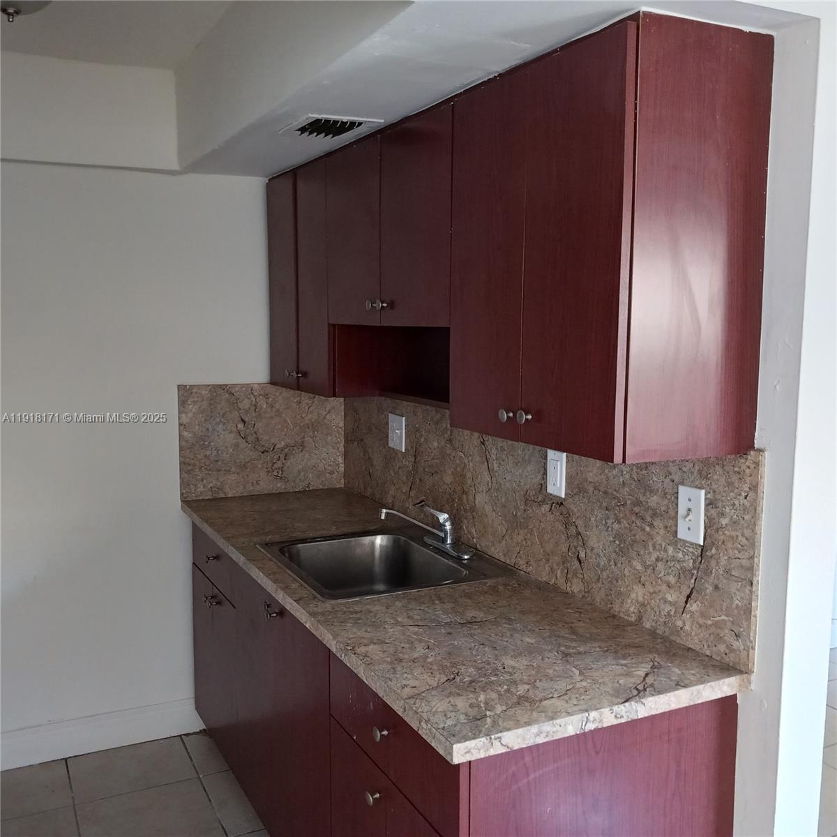 A kitchen features dark wood cabinets, a stainless steel sink, and brown laminate countertops — 2108 NW 59th Ter # A, Lauderhill FL 33313, LAUDERHILL, FL