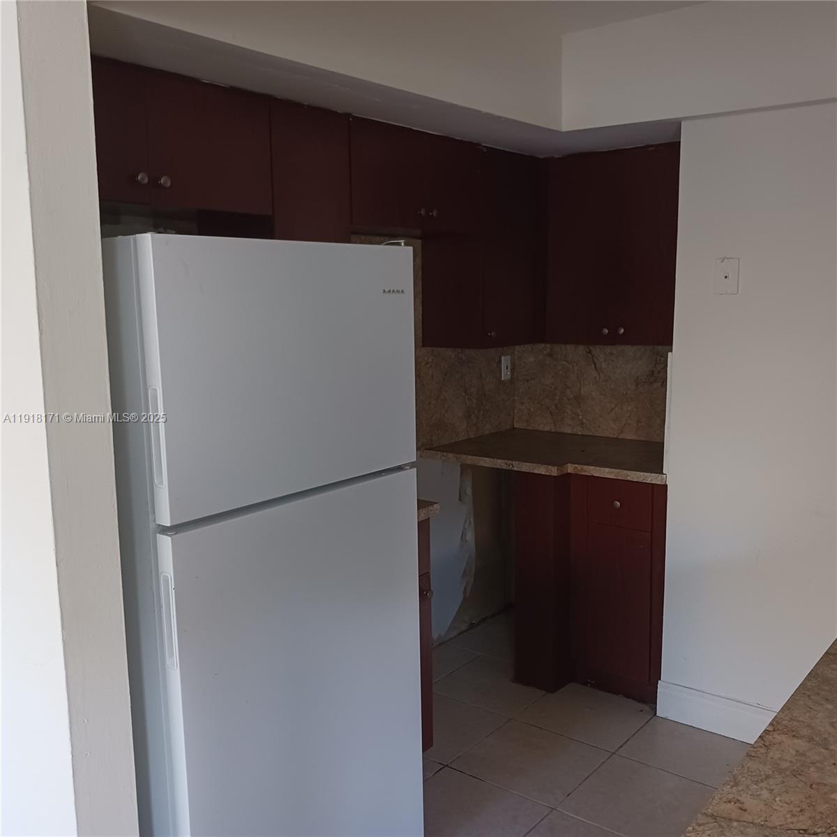 A white refrigerator stands next to dark wood cabinets and a stone-look countertop — 2108 NW 59th Ter # A, Lauderhill FL 33313, LAUDERHILL, FL