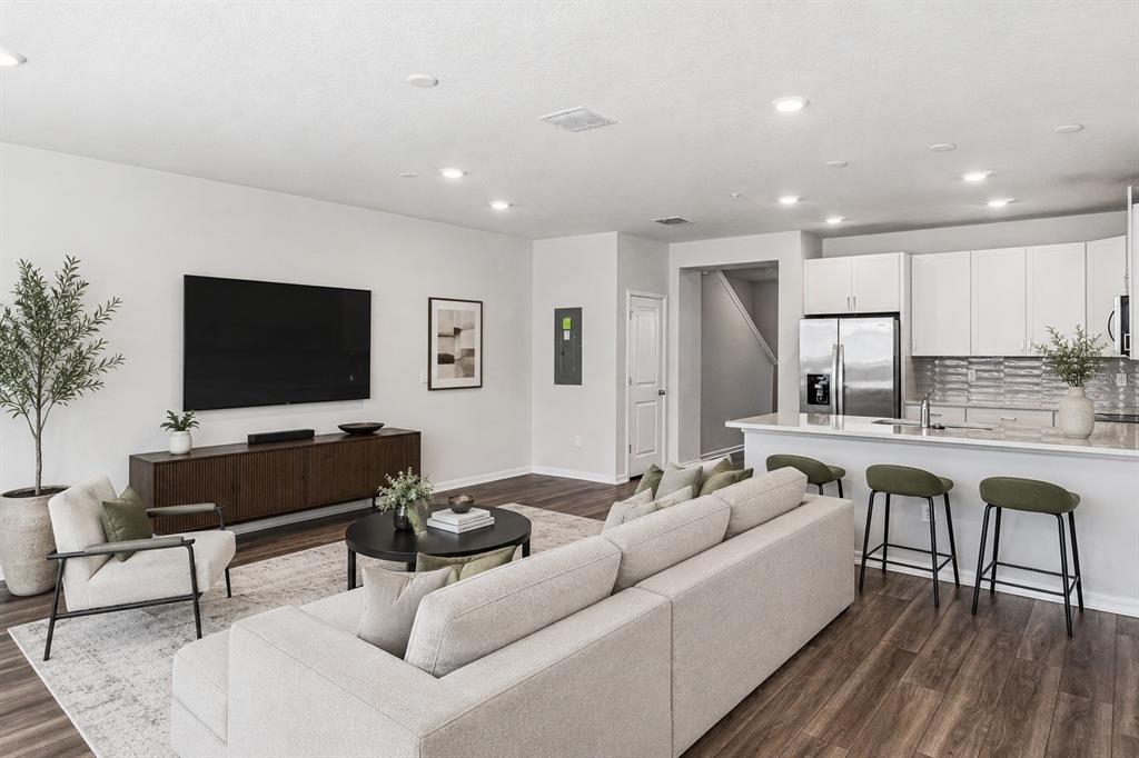 An open-concept living room and kitchen featuring a large sectional, television, and breakfast bar — 14375 SAPELO BEACH DRIVE, ORLANDO, FL