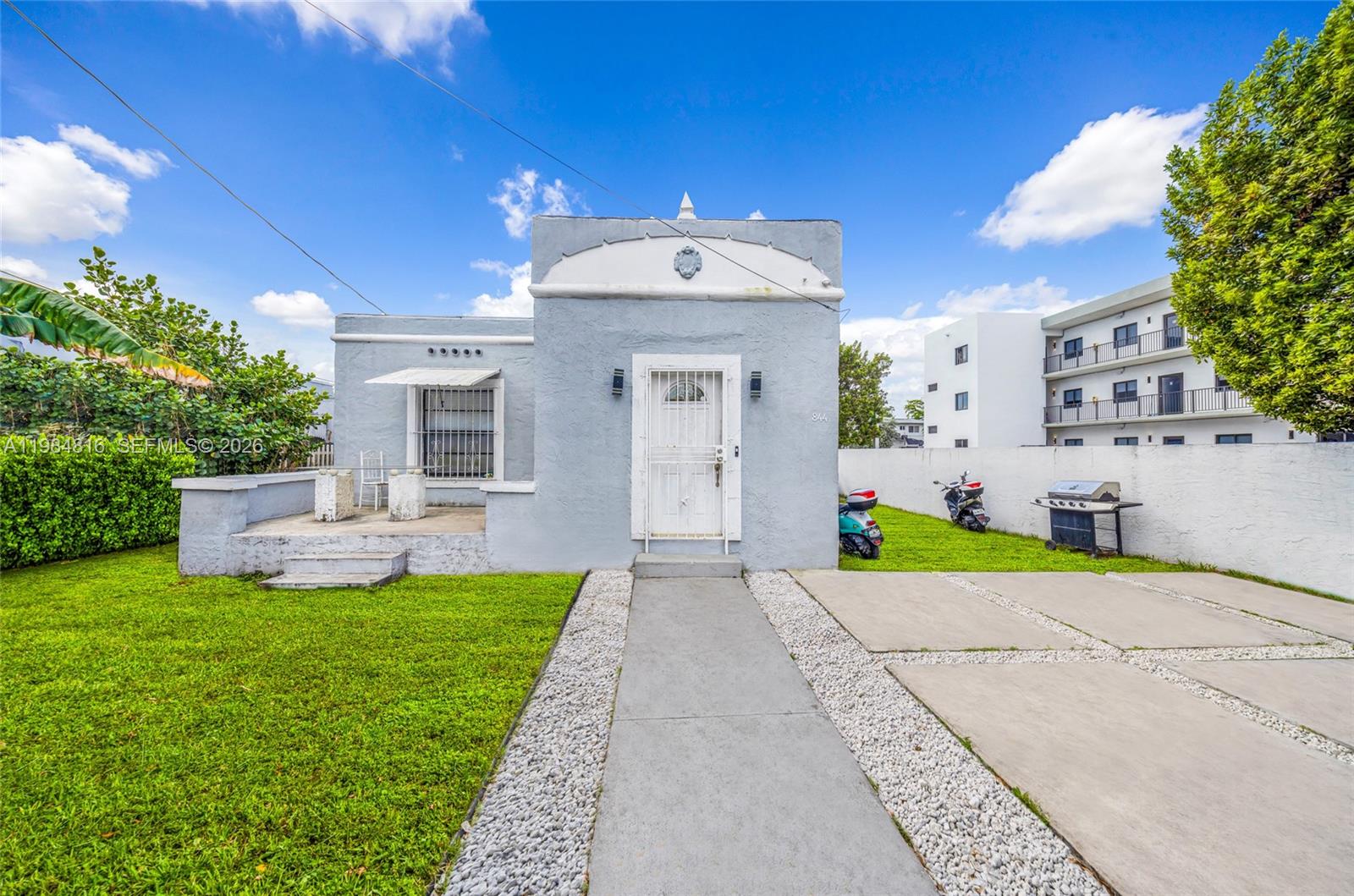 A light blue single-story house features a front porch, a walkway, and a concrete driveway — 844 NW 29th St, Miami FL 33127, MIAMI, FL
