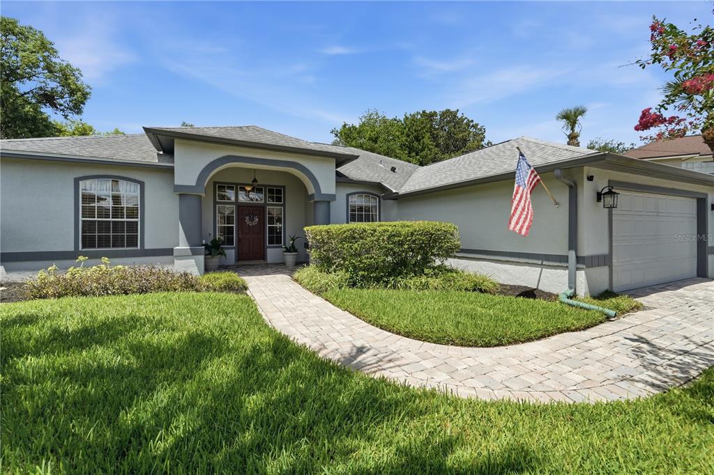A single-story house with a paved walkway, arched entryway, and an attached garage — 1053 OLD COVENTRY COURT, OVIEDO, FL