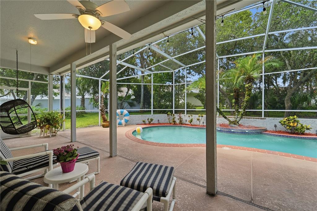 A covered patio with a ceiling fan overlooks a screened-in swimming pool and backyard — 1053 OLD COVENTRY COURT, OVIEDO, FL