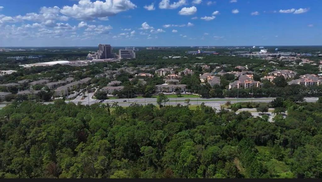 An aerial view shows a multi-lane road bordered by trees, a parking lot, and buildings — 13709 S APOPKA VINELAND ROADS, ORLANDO, FL