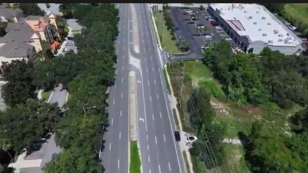 An aerial view of a lake surrounded by dense trees under a blue sky — 13709 S APOPKA VINELAND ROADS, ORLANDO, FL