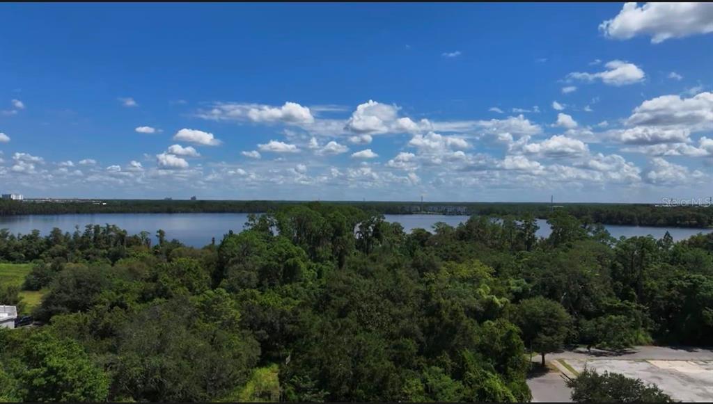 An aerial view shows a tall apartment building situated next to a large lake — 13709 S APOPKA VINELAND ROADS, ORLANDO, FL